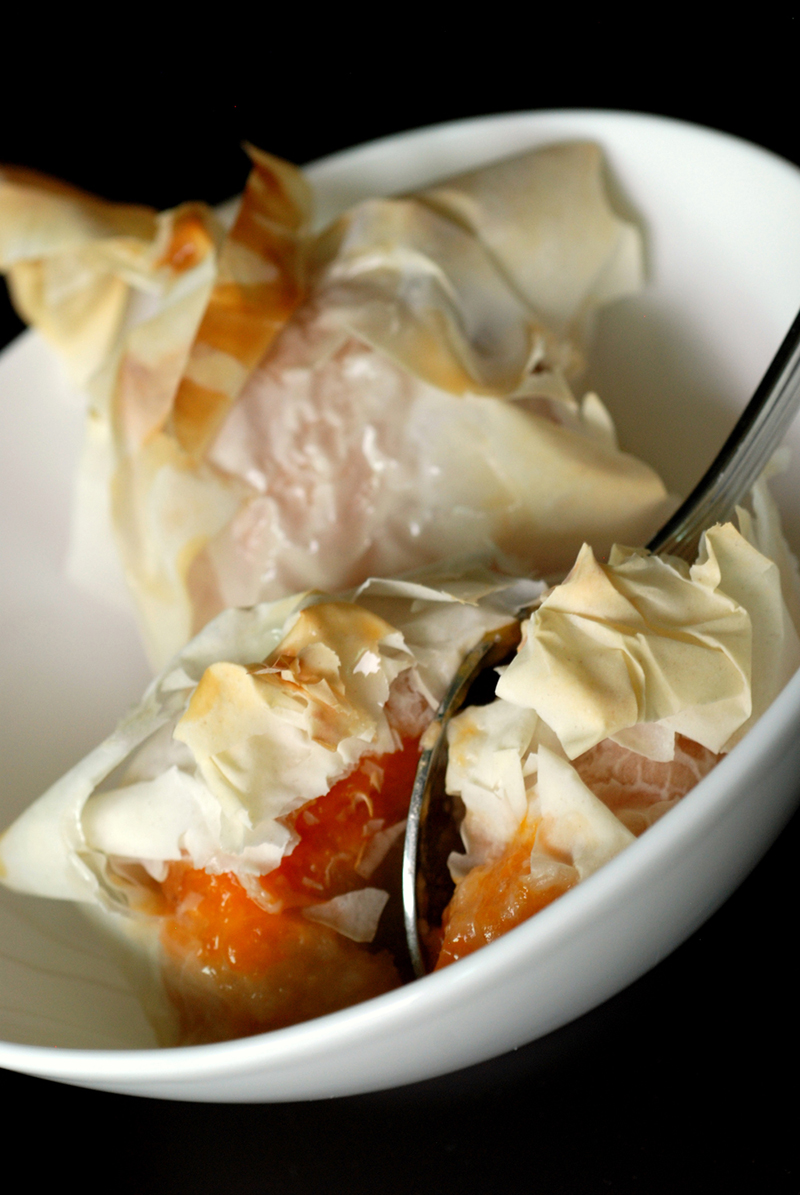 A bowl of apricot parcels with honey glaze and a spoon