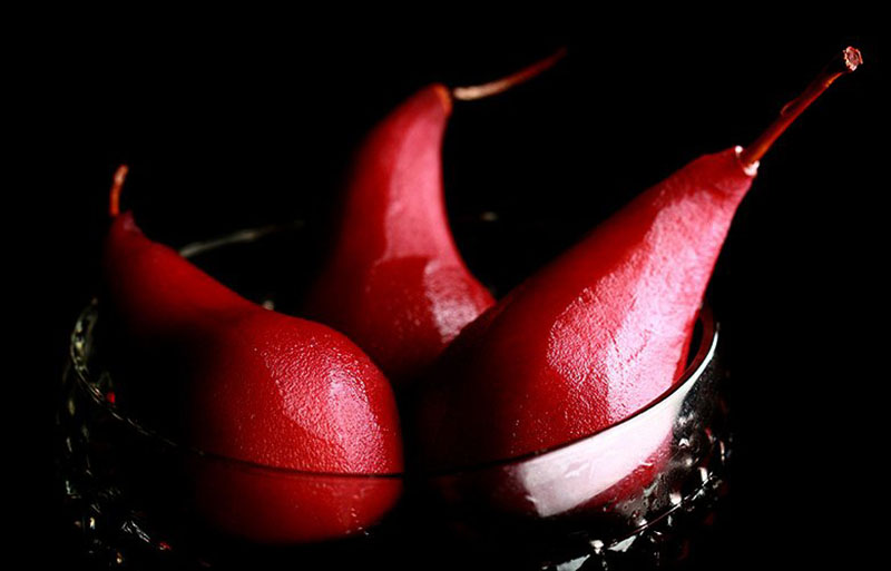 Three red poached pears in a dish