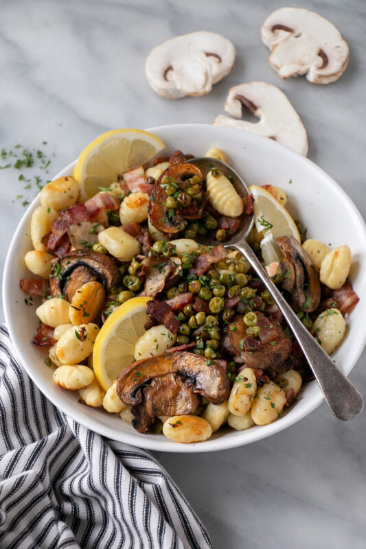 Gnocchi with peas and mushrooms in a bowl.